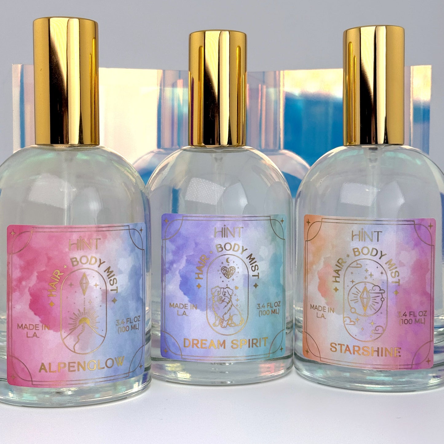 Three bottles of HINT body mist with colorful labels on a white background