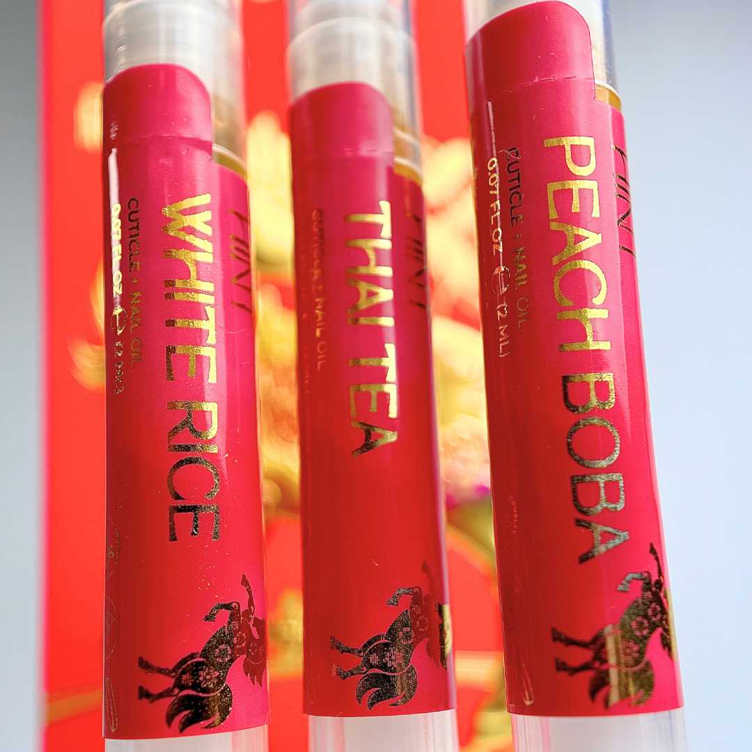 Three cuticle oil twist pens labeled 'White Rice', 'Thai Tea', and 'Peach Boba' on a colorful background.