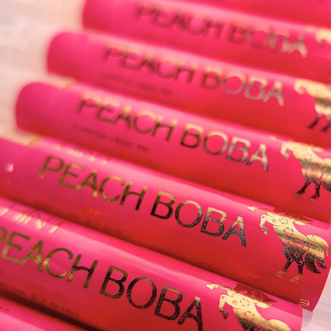 Multiple twist pens of Peach Boba cuticle oil with a red color scheme.