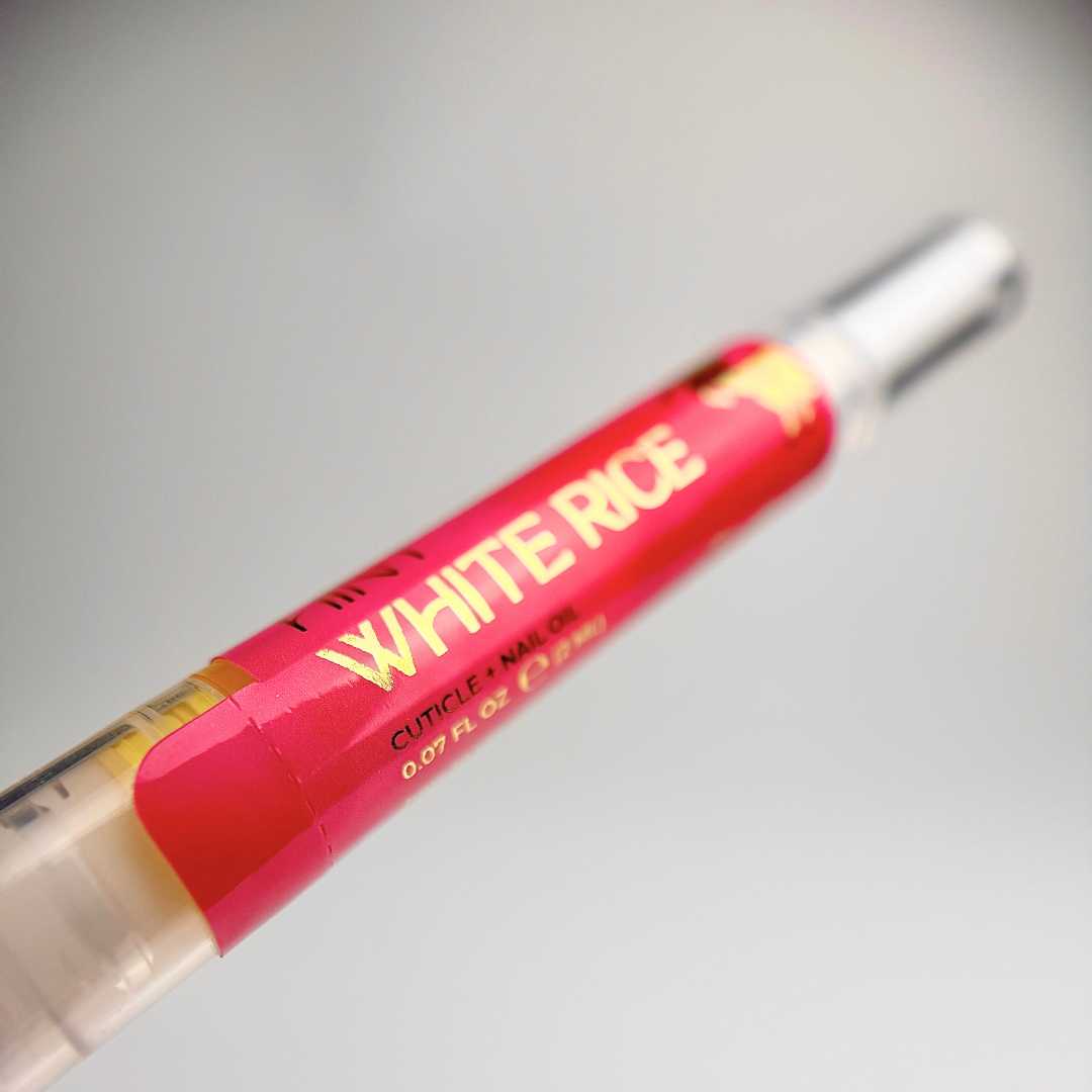 White Rice cuticle oil twist pen with red label on a light gray background
